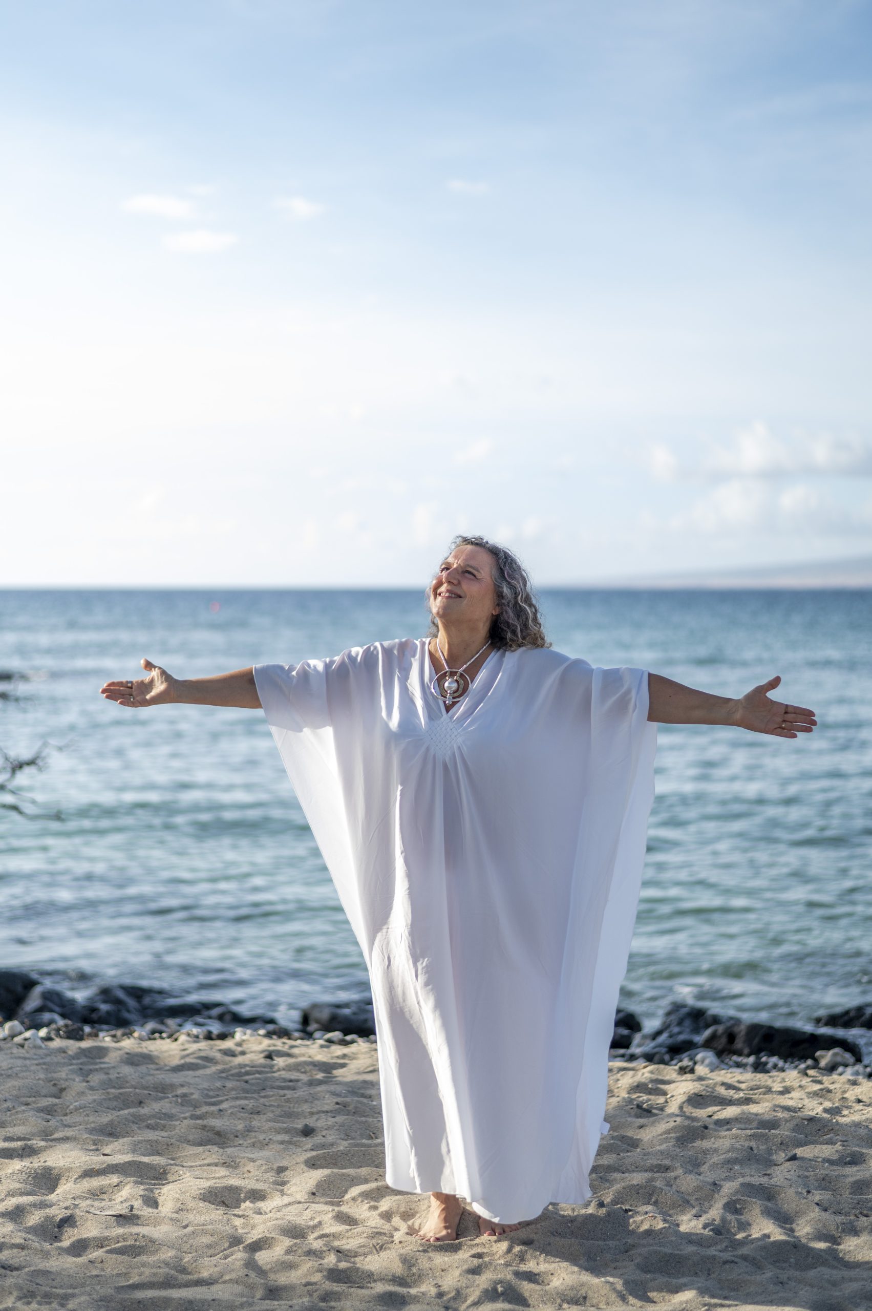 Shakti facing the ocean in a white robe