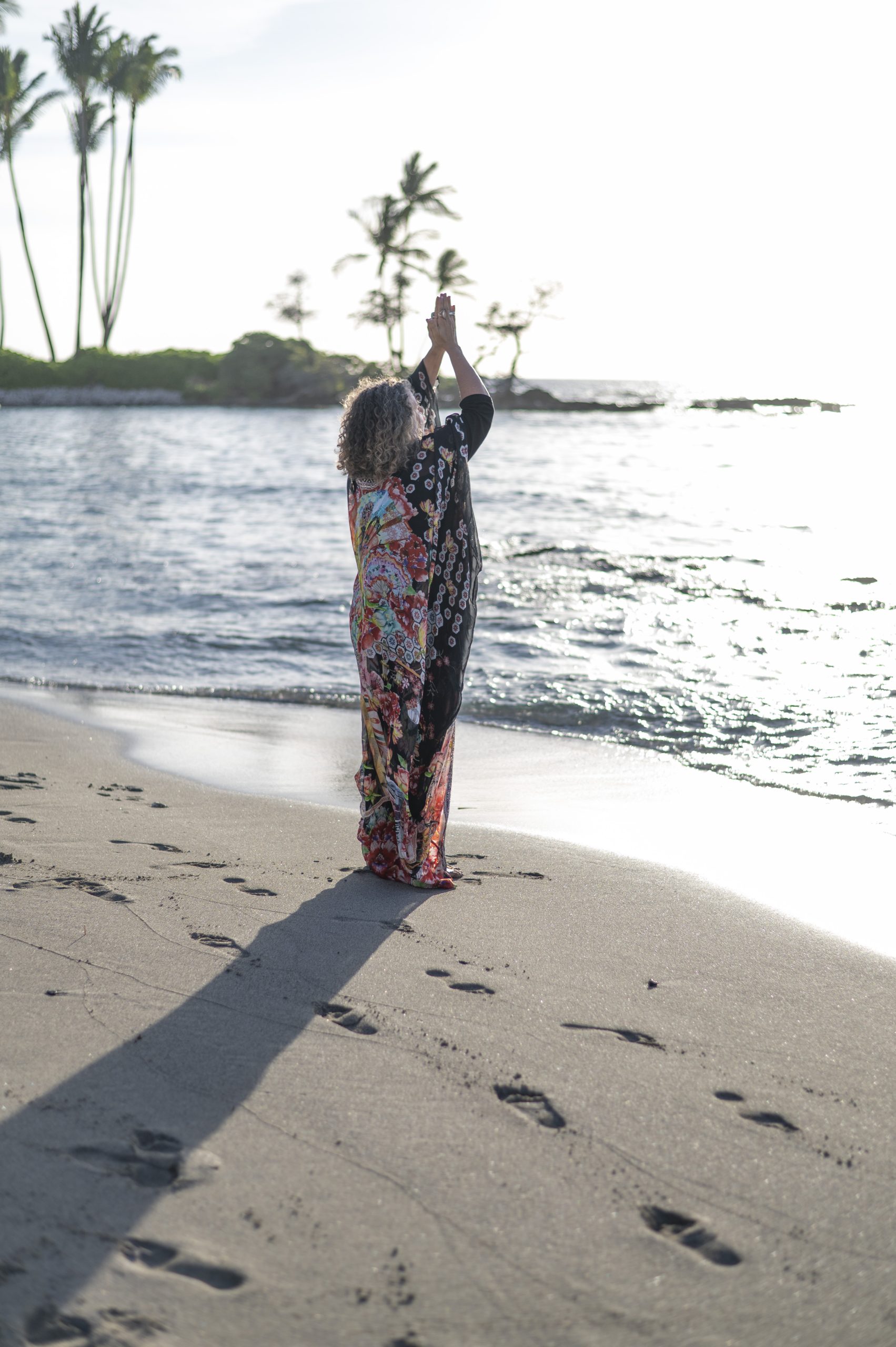 Shakti on the beach with hands raised toward the sky