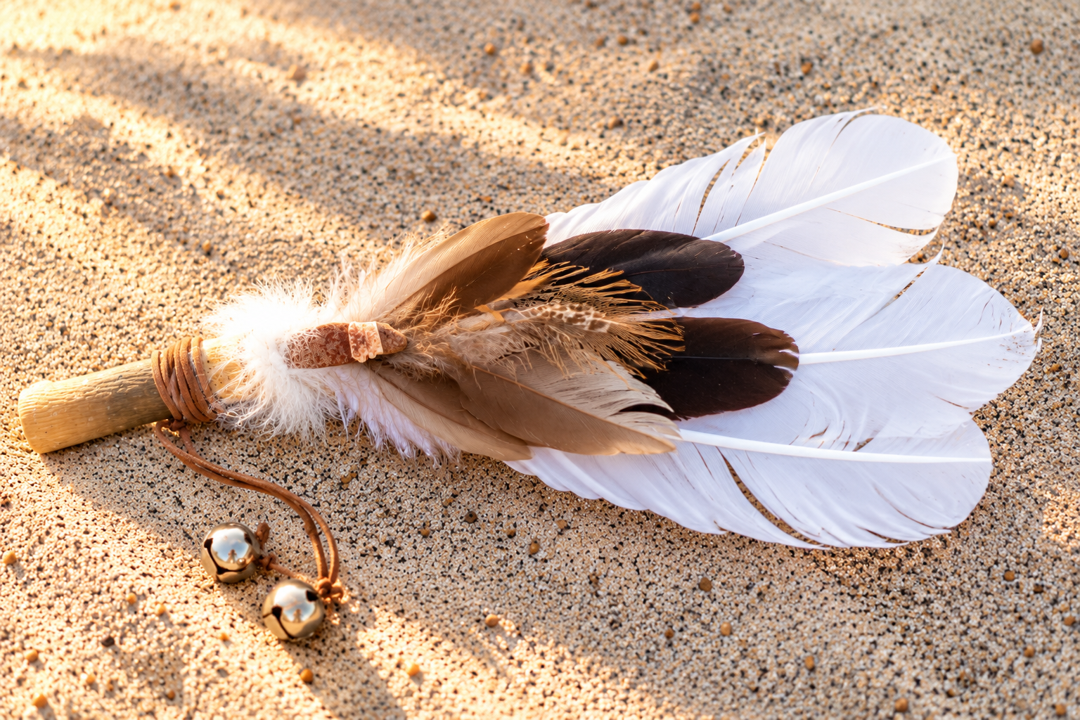 Sacred feather fan resting on sand in soft sunlight